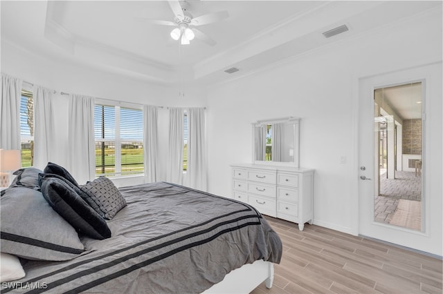 bedroom with light wood-type flooring, a raised ceiling, crown molding, and ceiling fan