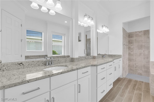 bathroom with vanity, ornamental molding, hardwood / wood-style flooring, and a tile shower