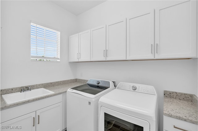 laundry room featuring washing machine and clothes dryer, cabinets, and sink