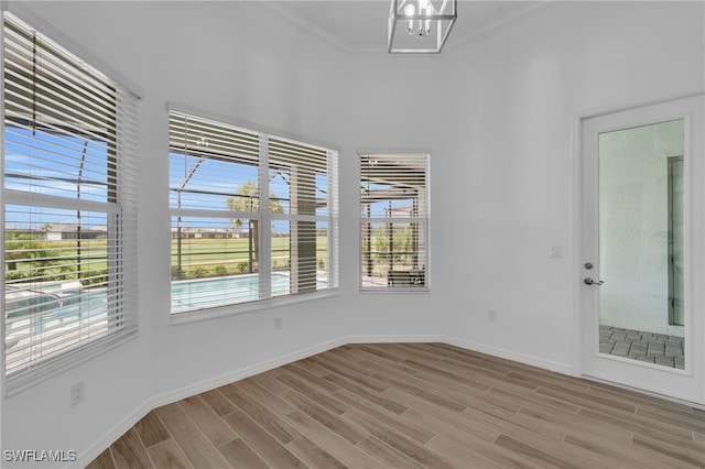 unfurnished room featuring crown molding, light hardwood / wood-style flooring, and a notable chandelier