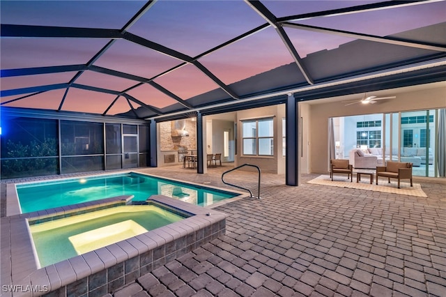 pool at dusk featuring a lanai, an in ground hot tub, ceiling fan, and a patio