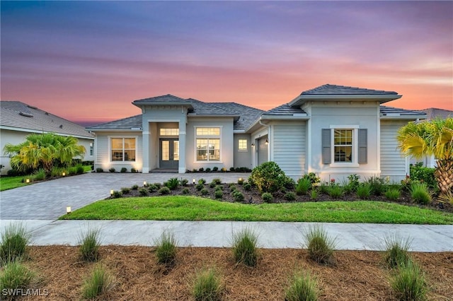 prairie-style home with decorative driveway, an attached garage, and french doors