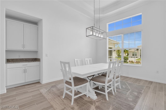 dining space with crown molding, an inviting chandelier, and light wood-type flooring