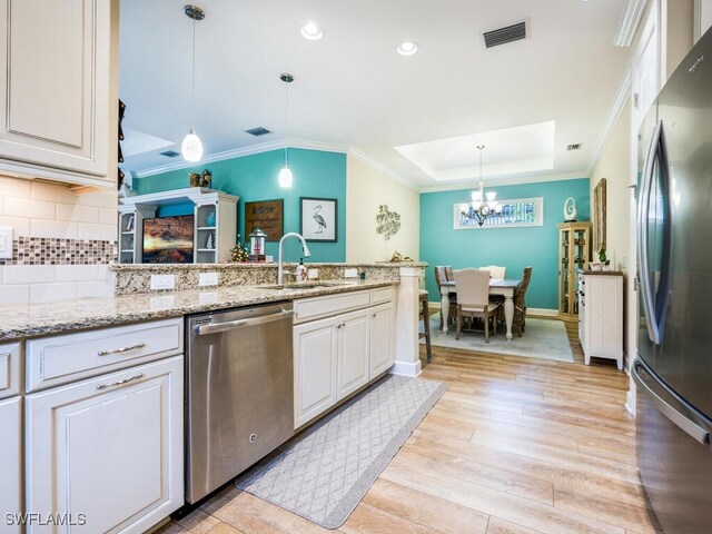 kitchen featuring pendant lighting, sink, light wood-type flooring, light stone counters, and stainless steel appliances