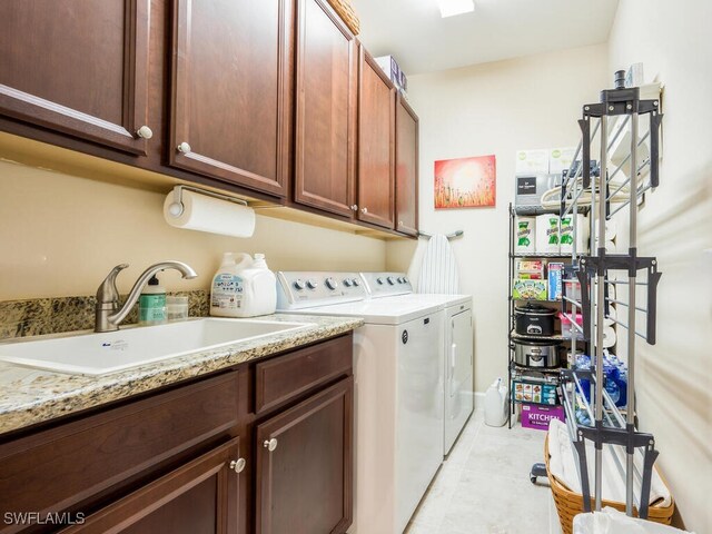 laundry area with washing machine and clothes dryer, sink, light tile patterned floors, and cabinets