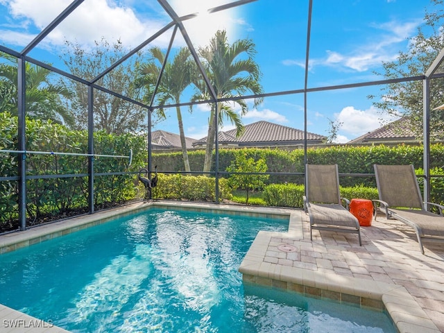 outdoor pool featuring glass enclosure and a patio