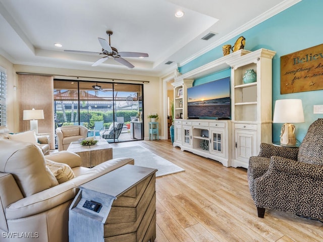 living room featuring a tray ceiling, crown molding, built in features, and hardwood / wood-style flooring