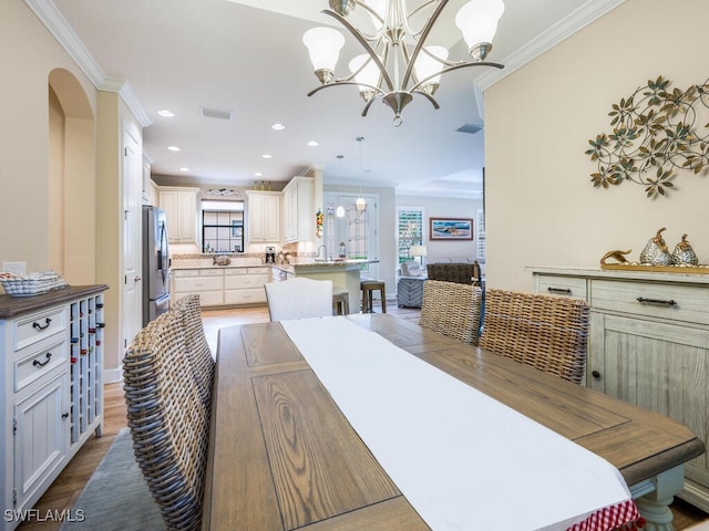 dining space featuring hardwood / wood-style floors, an inviting chandelier, and ornamental molding