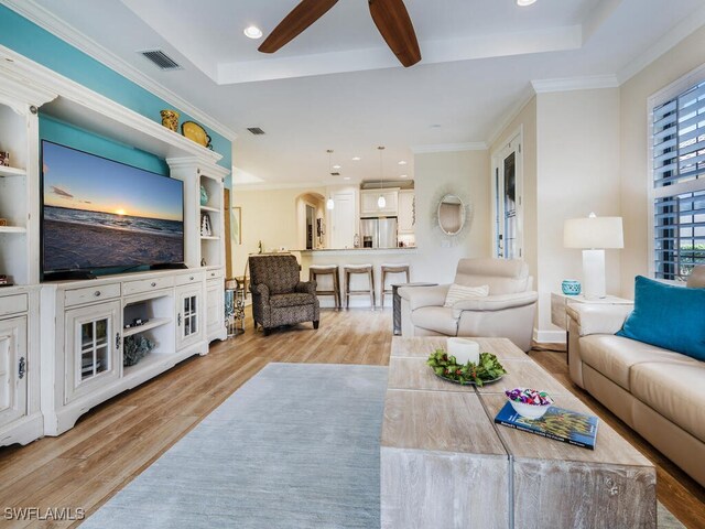 living room featuring ceiling fan, light hardwood / wood-style floors, and crown molding