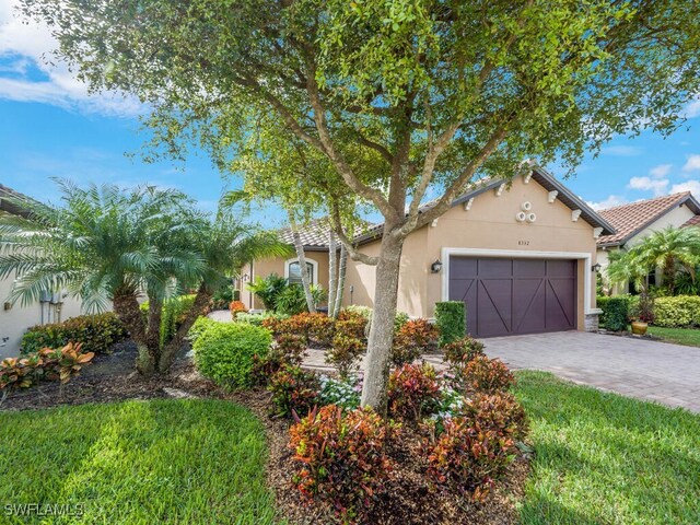 view of front of house with decorative driveway, a tile roof, an attached garage, and stucco siding