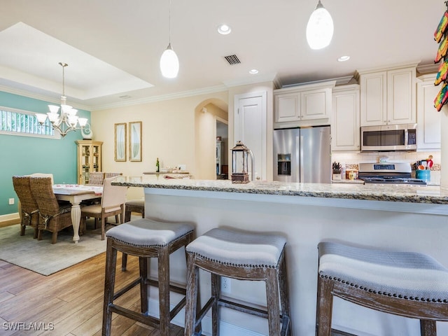 kitchen featuring pendant lighting, light stone countertops, and stainless steel appliances