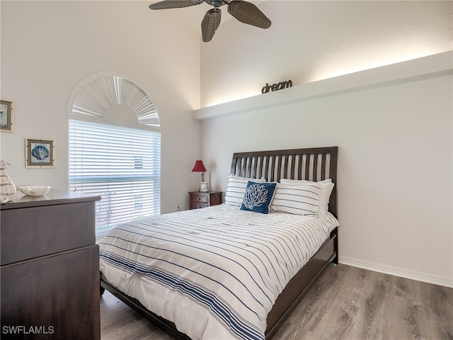 bedroom featuring ceiling fan, hardwood / wood-style floors, and a high ceiling