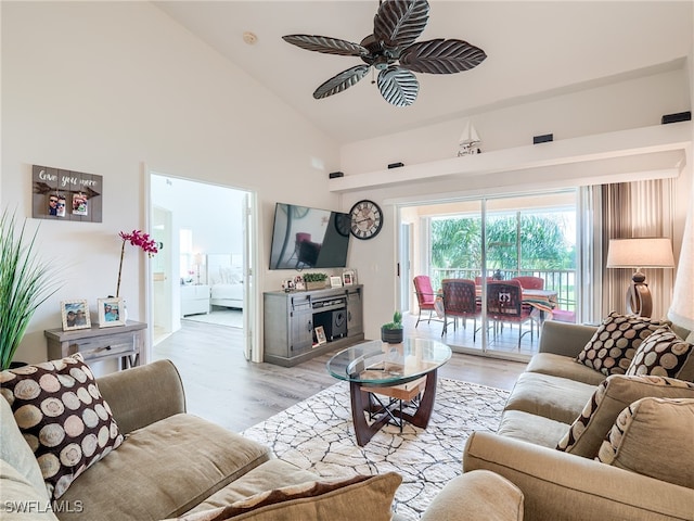 living room with light wood-type flooring, high vaulted ceiling, and ceiling fan