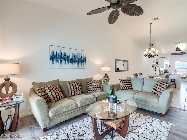 living room with high vaulted ceiling, ceiling fan with notable chandelier, and hardwood / wood-style flooring