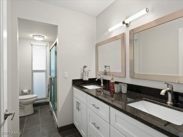 bathroom with toilet, tile patterned floors, vanity, a textured ceiling, and a shower with shower door