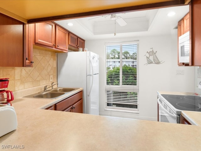 kitchen with a tray ceiling, crown molding, white appliances, and sink