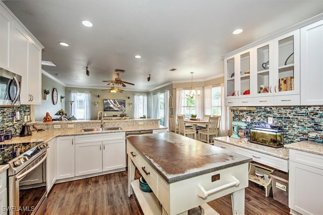 kitchen with hanging light fixtures, appliances with stainless steel finishes, sink, kitchen peninsula, and ceiling fan