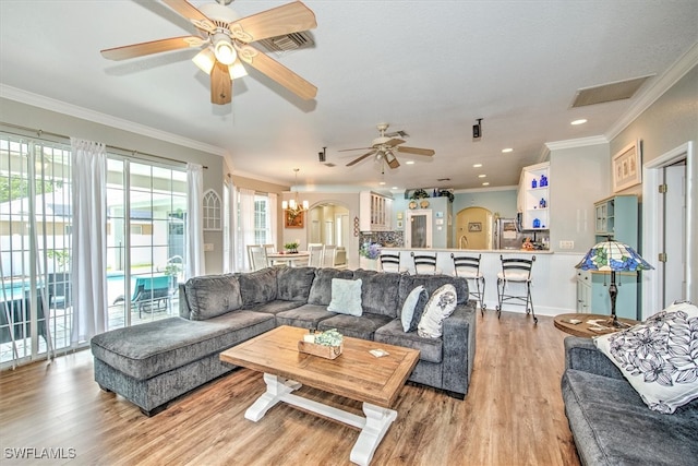 living room with ceiling fan with notable chandelier, crown molding, and light hardwood / wood-style flooring