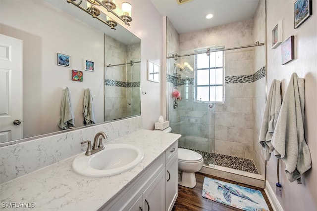 bathroom with vanity, toilet, hardwood / wood-style floors, and a shower with door