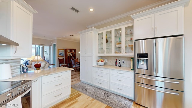 kitchen featuring stainless steel appliances, white cabinets, light wood-type flooring, and tasteful backsplash