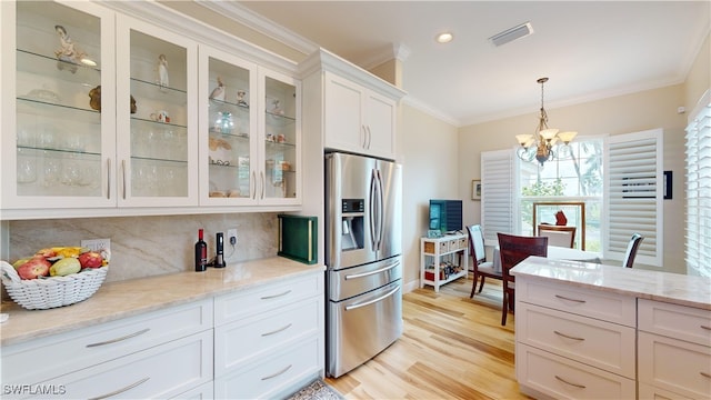 kitchen featuring stainless steel fridge with ice dispenser, a notable chandelier, white cabinetry, hanging light fixtures, and decorative backsplash