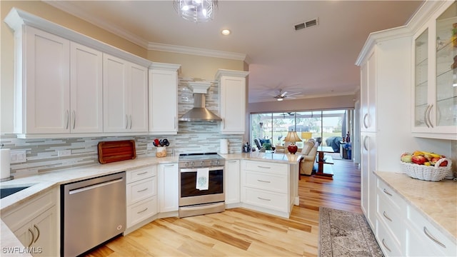 kitchen featuring stainless steel appliances, white cabinetry, light wood-type flooring, and wall chimney range hood