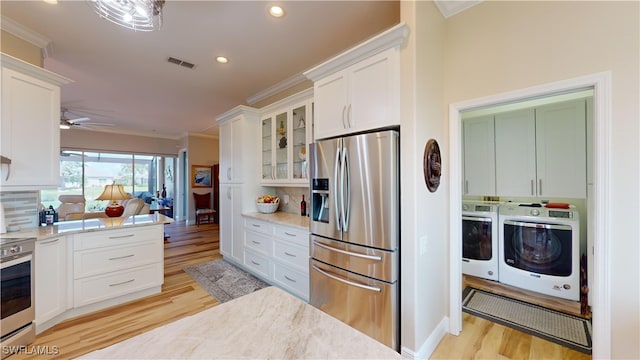 kitchen with white cabinets, backsplash, separate washer and dryer, stainless steel appliances, and ornamental molding