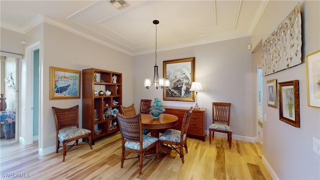 dining area featuring light hardwood / wood-style flooring, crown molding, and a chandelier