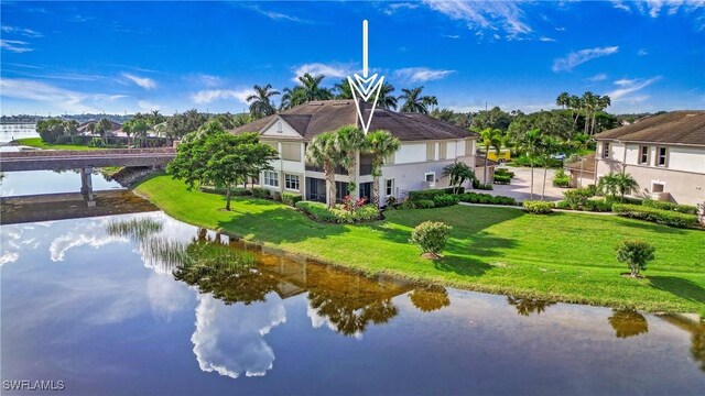 back of house featuring a water view, a lawn, and stucco siding