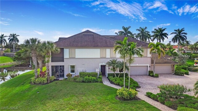 view of front of house with a water view, a front lawn, decorative driveway, and stucco siding