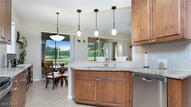 kitchen with hanging light fixtures, light stone counters, stainless steel appliances, and sink