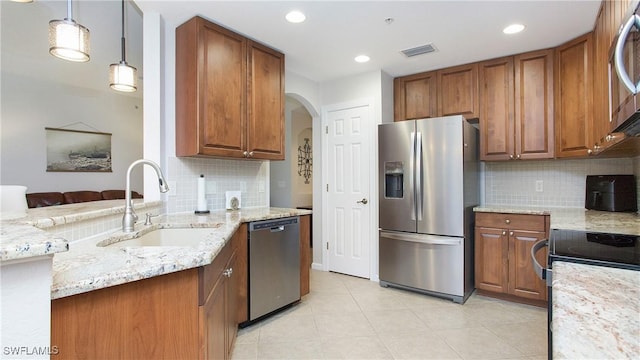 kitchen with visible vents, brown cabinetry, appliances with stainless steel finishes, light stone countertops, and a sink