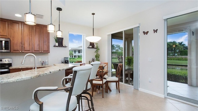 kitchen with tasteful backsplash, visible vents, appliances with stainless steel finishes, brown cabinets, and light stone counters