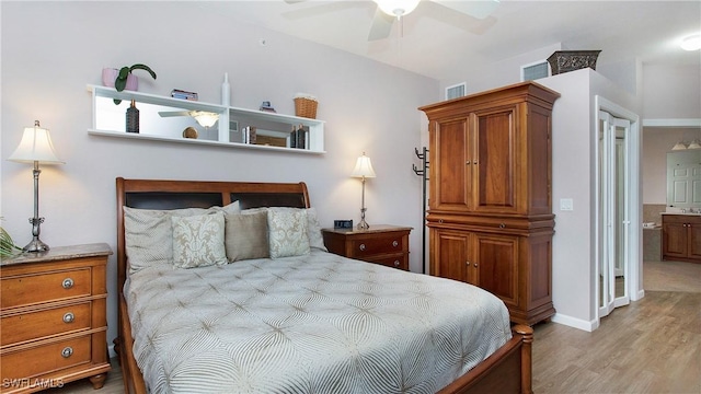 bedroom featuring ceiling fan, visible vents, baseboards, light wood-style floors, and ensuite bath