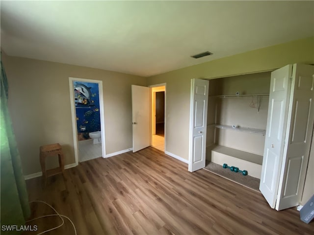 unfurnished bedroom with a closet, connected bathroom, and hardwood / wood-style floors