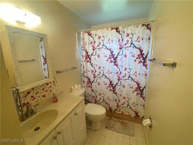 bathroom with a shower with shower curtain, vanity, toilet, and tile patterned floors