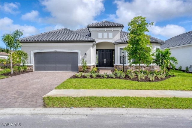 11902 Raggio Dr, Fort Myers, FL 33913 - mediterranean / spanish house with stone siding, a garage, decorative driveway, and stucco siding