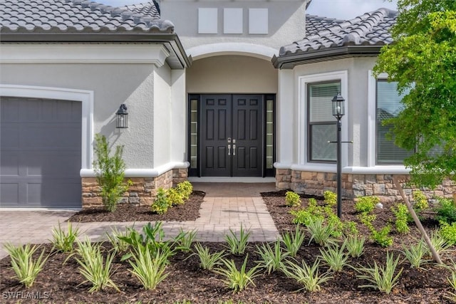 11902 Raggio Dr, Fort Myers, FL 33913 - view of exterior entry with stone siding, a tiled roof, a garage, and stucco siding