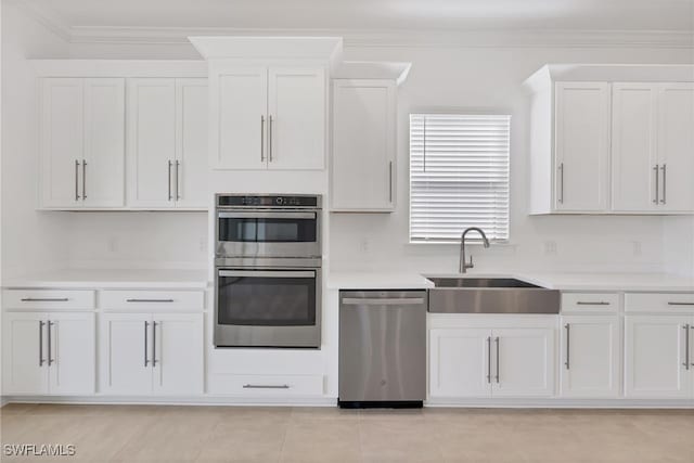 kitchen with light tile patterned floors, appliances with stainless steel finishes, white cabinetry, sink, and ornamental molding