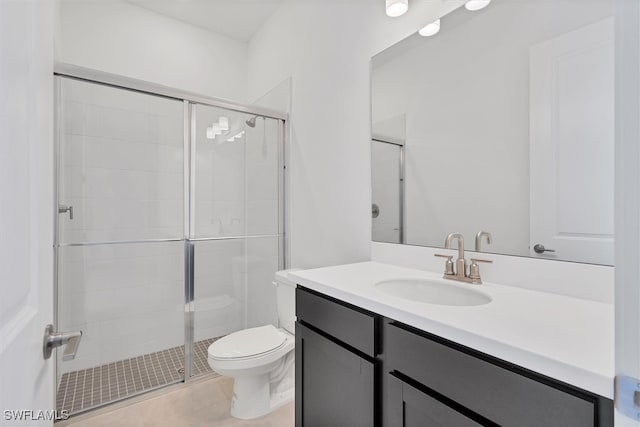 bathroom featuring tile patterned flooring, toilet, a shower with door, and vanity