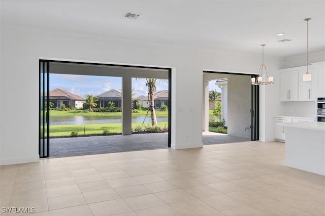 unfurnished living room with light tile patterned floors, a water view, and an inviting chandelier