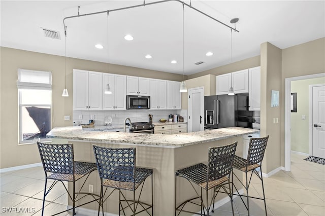 kitchen featuring light stone countertops, light tile patterned floors, backsplash, stainless steel appliances, and white cabinets