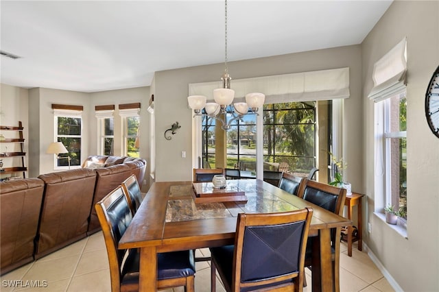 tiled dining room with a healthy amount of sunlight and an inviting chandelier