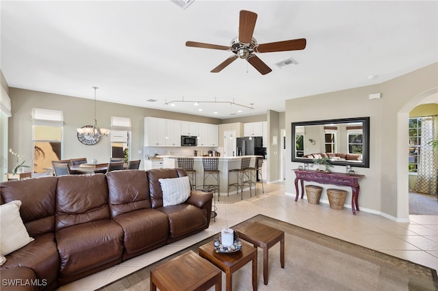 living room featuring ceiling fan with notable chandelier and light tile patterned floors