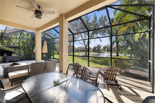 view of patio / terrace featuring a water view, ceiling fan, and a lanai