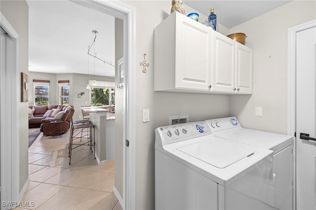 washroom featuring light tile patterned floors, cabinets, and washing machine and dryer