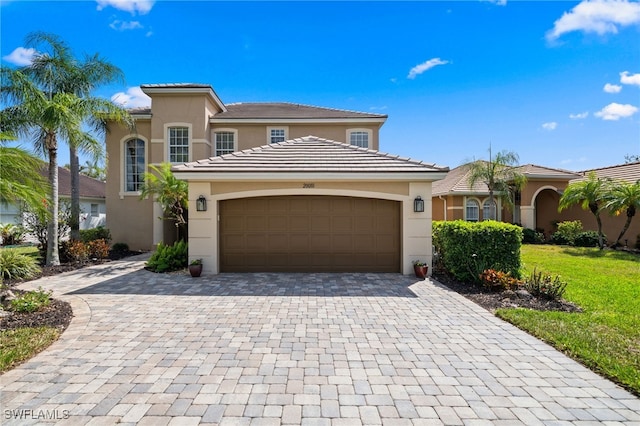 mediterranean / spanish house featuring a tile roof, stucco siding, decorative driveway, and an attached garage