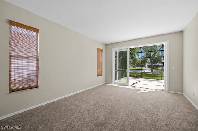 carpeted empty room featuring baseboards