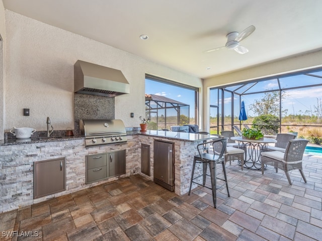 kitchen with sink, kitchen peninsula, stainless steel refrigerator, wall chimney exhaust hood, and ceiling fan