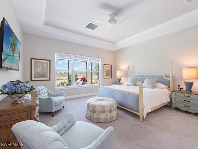 bedroom with a raised ceiling, light carpet, and ceiling fan